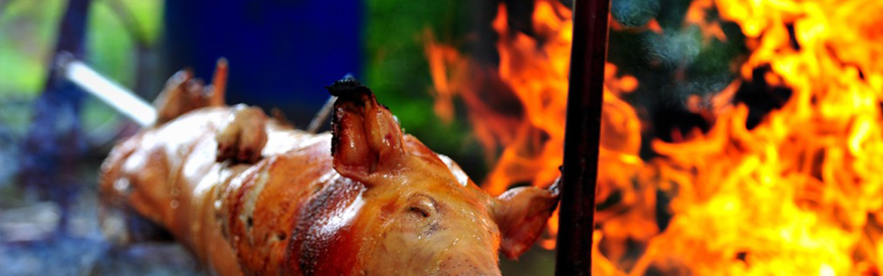 Cochon rôti au tournebroche devant les flammes
